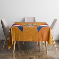Orange rectangular tablecloth with crest panel and blue triangle accents on the table