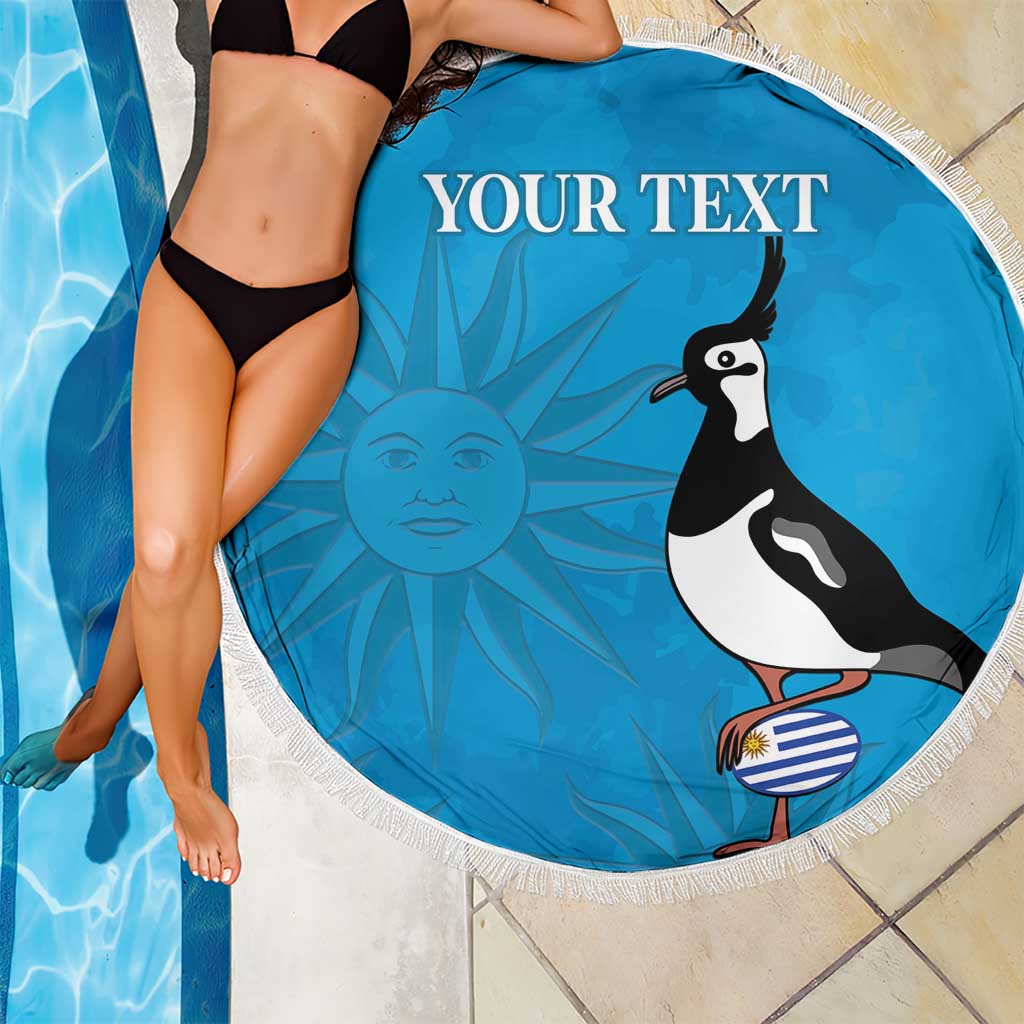 Blue round beach blanket with white fringe, “YOUR TEXT” and bird graphic by the pool