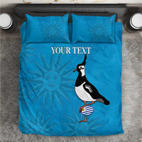 Blue duvet cover and pillowcases with sunburst pattern and penguin holding striped bottle