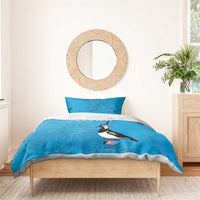 Blue bedding set with two pillowcases, penguin holding striped bottle, sun graphic