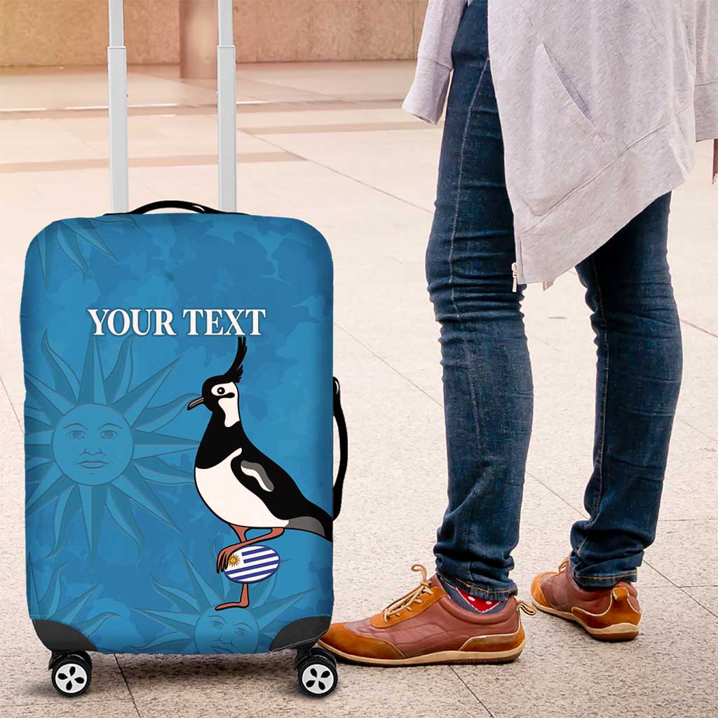 Blue luggage cover with bird and sunburst print on wheeled suitcase near standing person