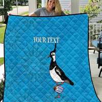 Blue quilt held outdoors with penguin graphic and 'Your text' across the center.