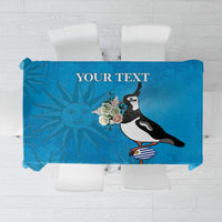 Blue tablecloth with illustrated penguin, flowers, and sunburst graphic centerpiece