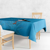 Blue tablecloth with penguin and sunburst pattern, centered on a wooden dining table