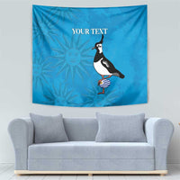 Blue tapestry with penguin, striped ball, and repeated sun faces pattern