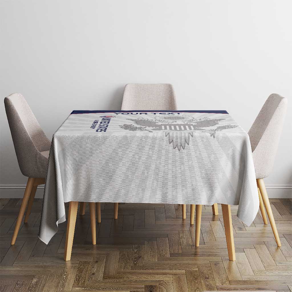 White custom tablecloth on dining table with blue-trimmed eagle design at center