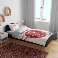 White bedding set with duvet and pillowcases; pink blossom print over red rugby design