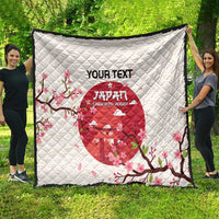 White quilt blanket outdoors with red Japan Under-20 rugby emblem, cherry blossoms, black edge.