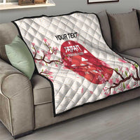 White quilt blanket draped on gray couch with red Japan rugby emblem and cherry blossom design.