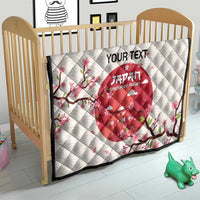 White quilt blanket on wooden baby bed with red Japan Under-20 rugby emblem and cherry blossoms.