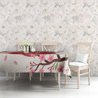 White tablecloth with pink blossoms and branch pattern spread across a dining table