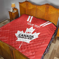 Red quilt on bed with white maple leaf and “CANADA UNDER-20 RUBY” center print