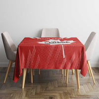 Red tablecloth covering table, showing centered white maple leaf and graphic pattern.
