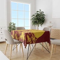 Gold and maroon palm-leaf tablecloth on rectangular table with chairs around it
