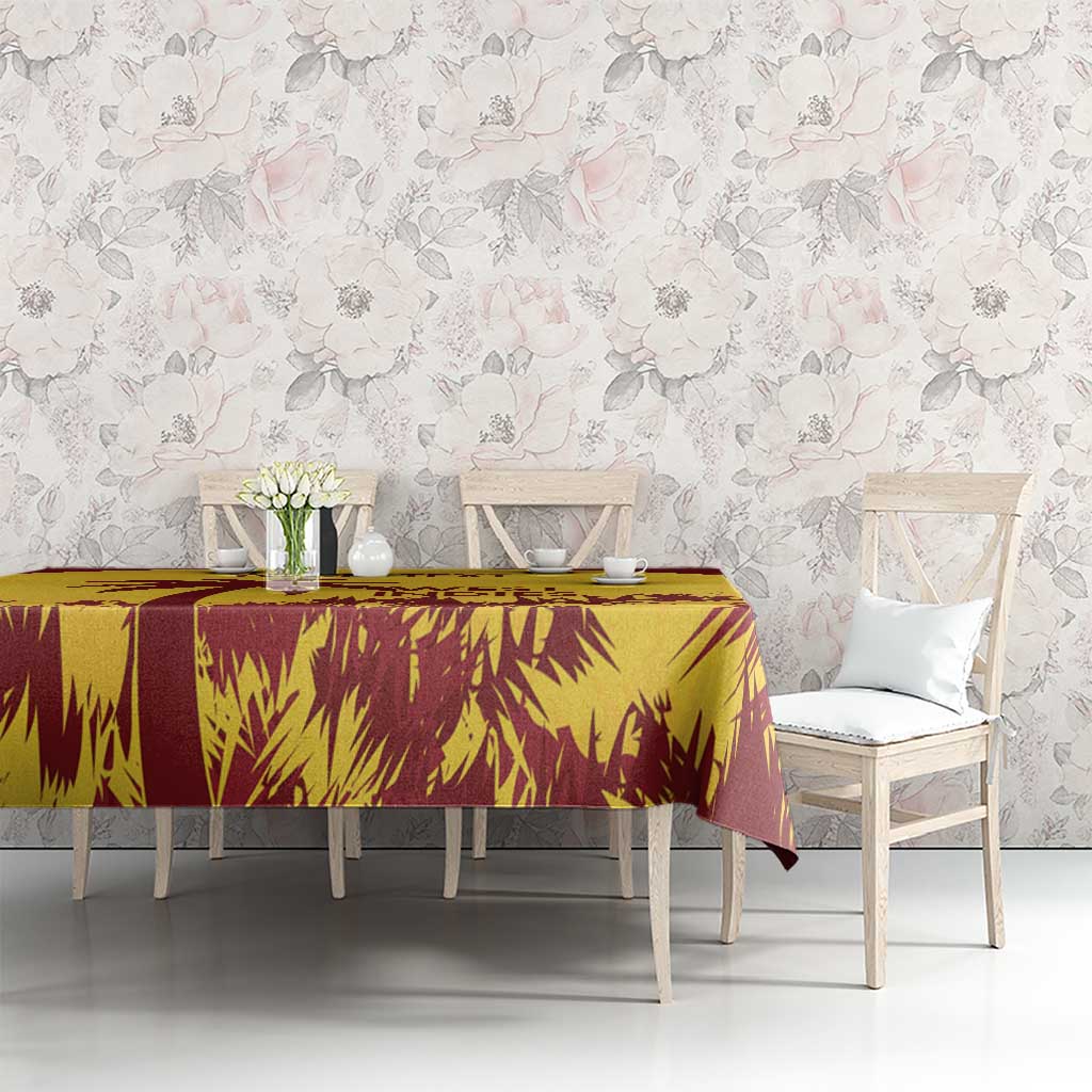 Gold and maroon tablecloth with palm-leaf print, draped over dining table