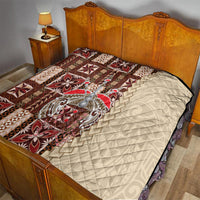 Bed quilt featuring brown, red, and cream tapa-inspired patchwork with cream quilted reverse.
