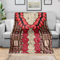 Samoa siapo blanket draped over sofa, red floral vines and brown geometric pattern with feather-like edges