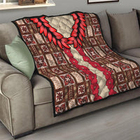 Brown quilt draped on a couch, featuring red leaf wreath and red floral stripe patchwork