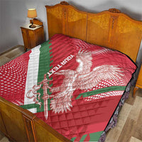 Red quilt on bed with eagle emblem, green diagonal stripe, and white border