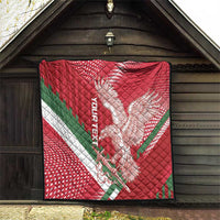 Red quilt hanging on porch wall, eagle design with white dots and green diagonal stripe