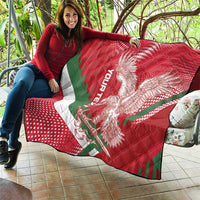 Red quilt spread on patio with eagle artwork, green diagonal stripe, and quilted squares