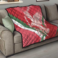 Red and green quilt on sofa with eagle graphic, white stripe, and stitched diamond pattern