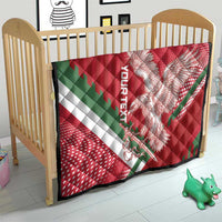 Red quilt on crib in nursery, eagle artwork with green diagonal stripe and white border