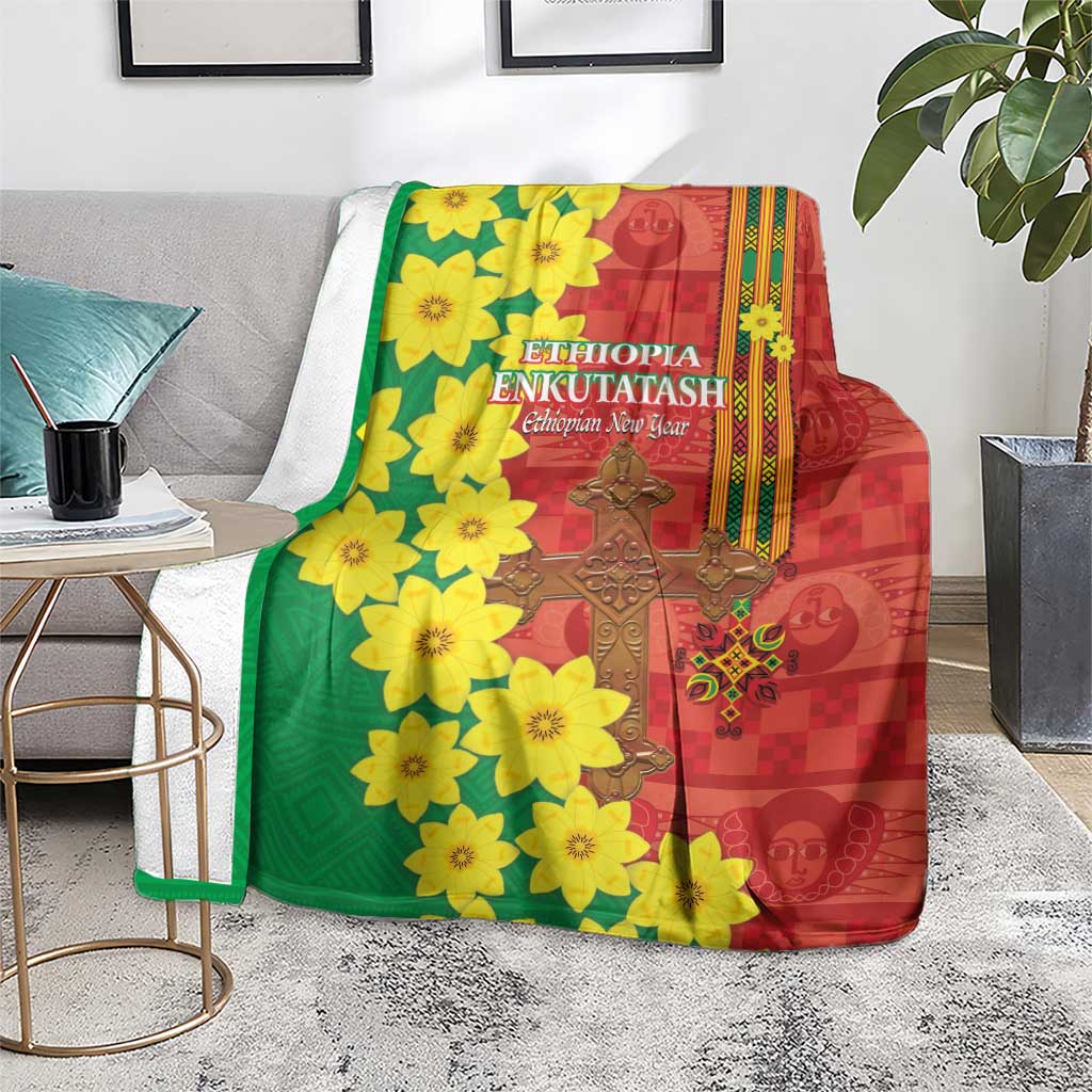 Red and green Ethiopian blanket on a gray sofa with yellow flower print and gold cross motif