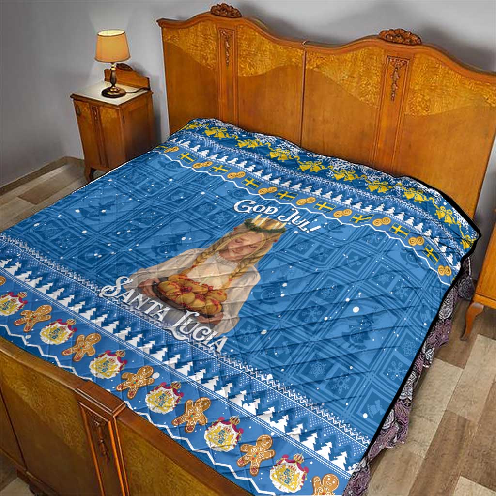 Blue Santa Lucia quilt laid on wooden bed, showing God Jul text and holiday border.
