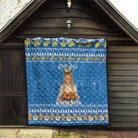 Blue God Jul Santa Lucia quilt draped on wooden wall with central portrait and ornament strip.