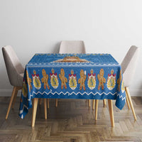 Blue holiday tablecloth covering dining table with repeating gingerbread figure design