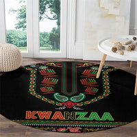Black round Kwanzaa carpet with green, red, and gold emblem and KWANZAA text
