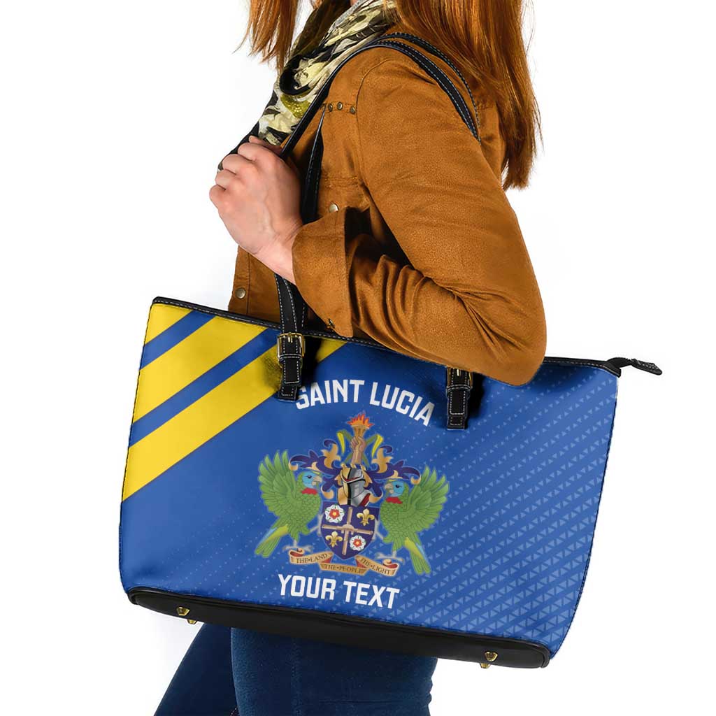 Blue tote with yellow stripe, Saint crest graphic, black zipper top, leather handles.