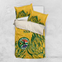 Folded yellow duvet and pillows with green leafy cricket design, Proteas crest, “YOUR TEXT”
