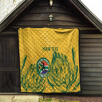 Yellow quilt hanging outdoors with diamond quilting and green leaf pattern, “YOUR TEXT”.