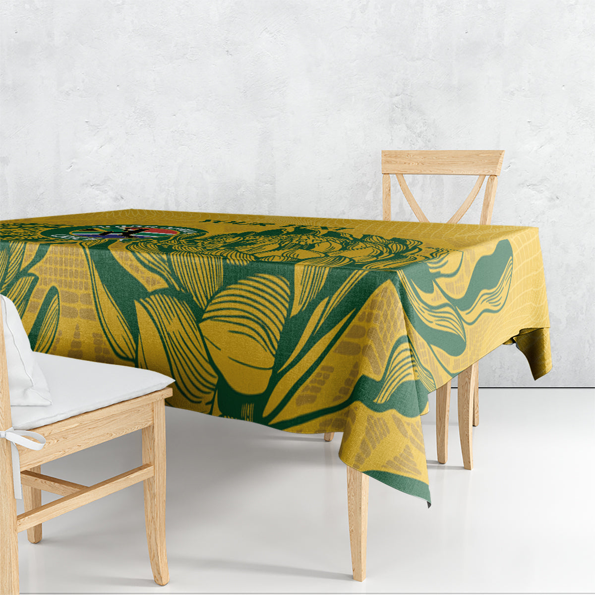 Yellow rectangular tablecloth with green leaf print draped over dining table