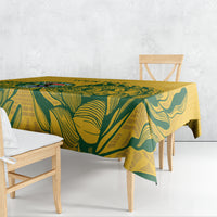 Yellow rectangular tablecloth with green leaf print draped over dining table