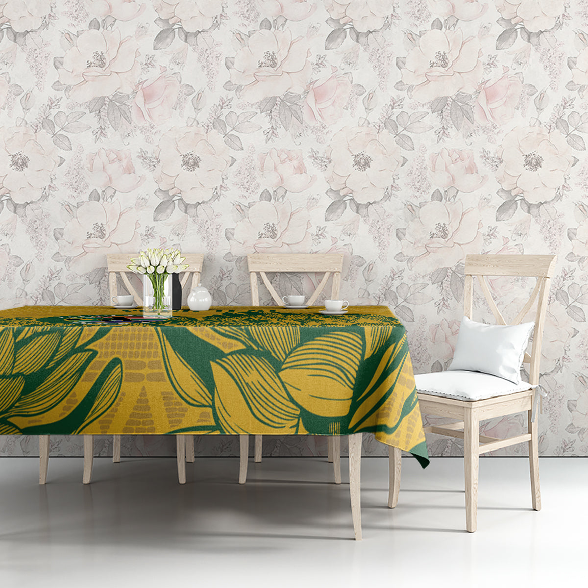 Yellow tablecloth with green leaf pattern on long dining table against floral wall