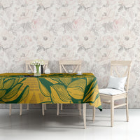 Yellow tablecloth with green leaf pattern on long dining table against floral wall