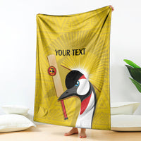 Yellow cricket blanket draped with crowned crane graphic and 'YOUR TEXT' in center