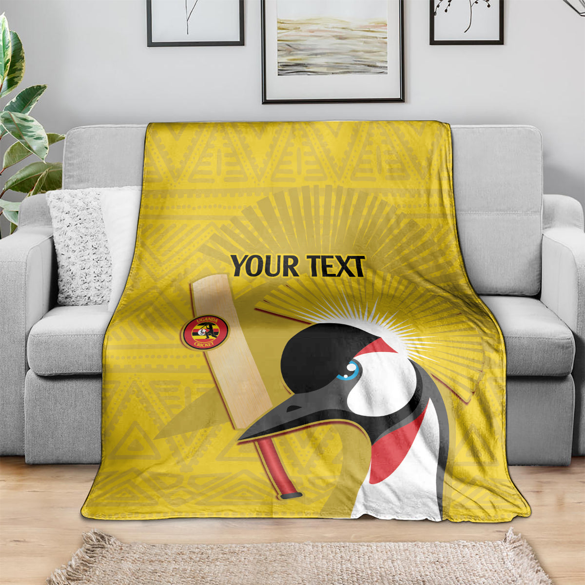 Yellow cricket blanket on sofa, crowned crane print with 'YOUR TEXT' text