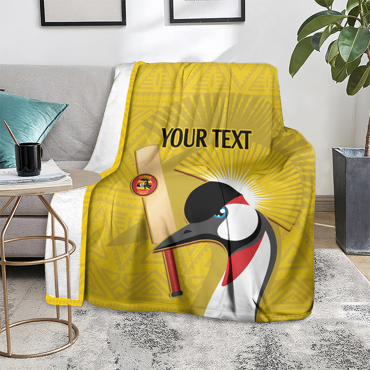 Yellow cricket blanket on chair, crowned crane graphic with 'YOUR TEXT'