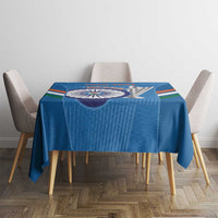 Blue tablecloth with centered cricket emblem and multi-color bands, on dining table