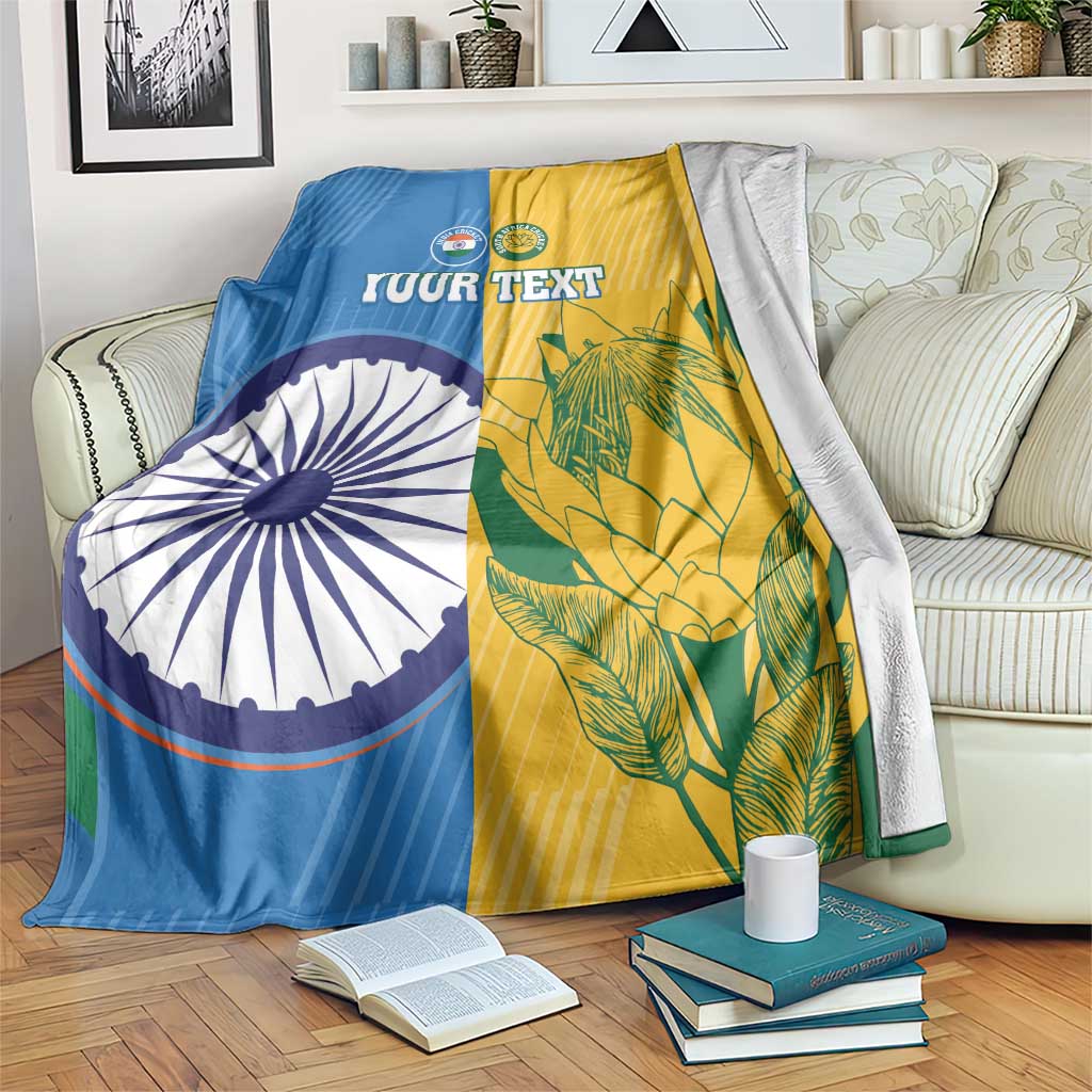 Cricket blanket on couch with blue-and-yellow halves, India-style wheel and tropical leaf graphics
