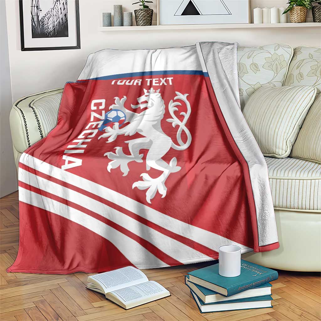 Red Czechia football blanket draped over sofa, featuring lion emblem, blue band, and stripes