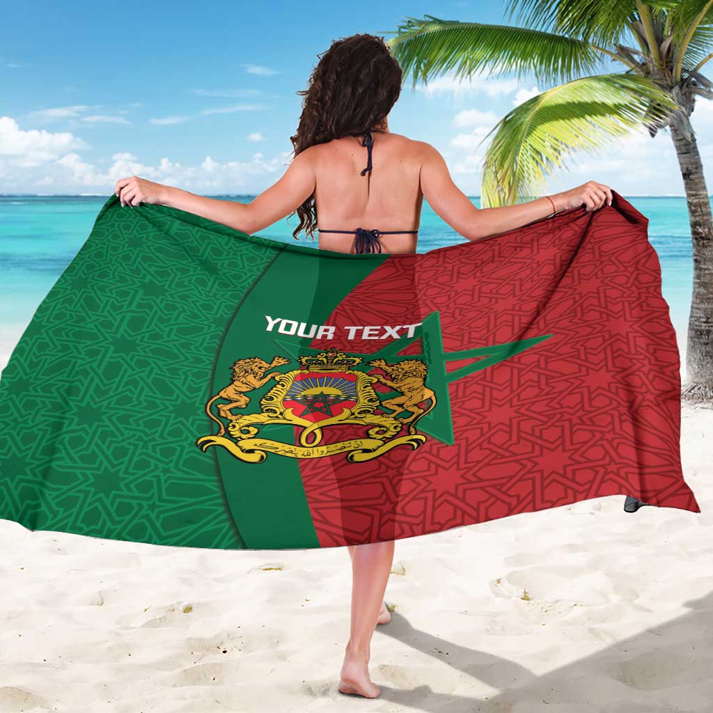 Personalised sarong draped over shoulders: green and red geometric pattern with crest
