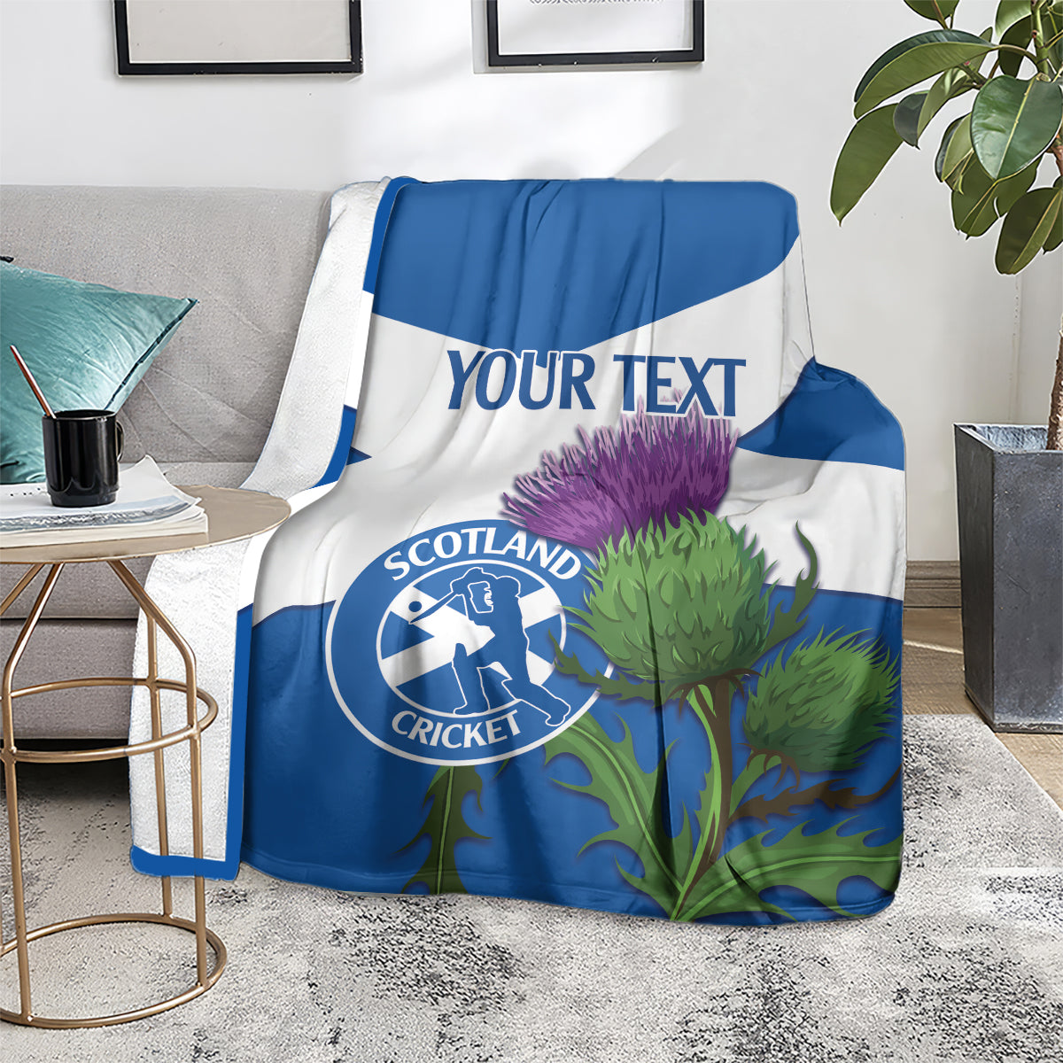 Blue and white Scotland cricket blanket on floor with thistle print and Scotland Cricket logo