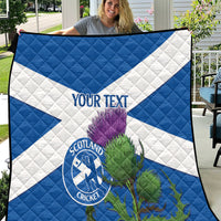 Blue and white quilt with Scotland Cricket emblem, thistle artwork, and 'YOUR TEXT'.