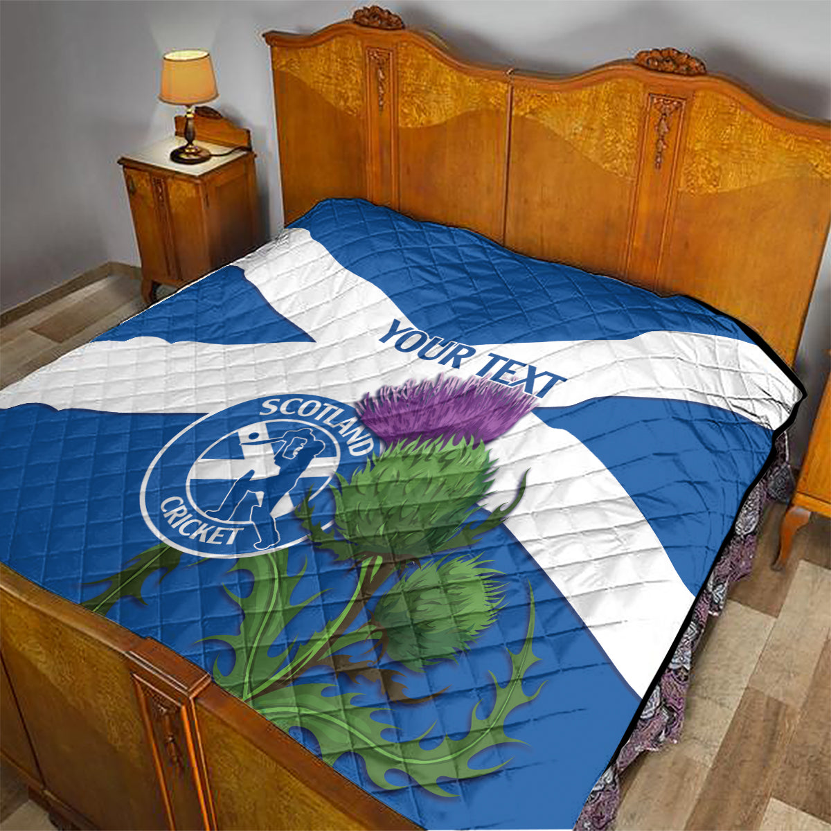 Blue and white quilt on bed with Scotland Cricket emblem, thistle artwork, and 'YOUR TEXT'.