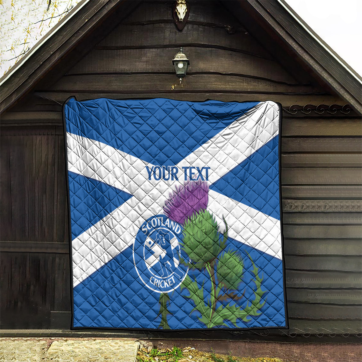 Blue and white quilt with Scotland Cricket emblem and thistle design on front panel.
